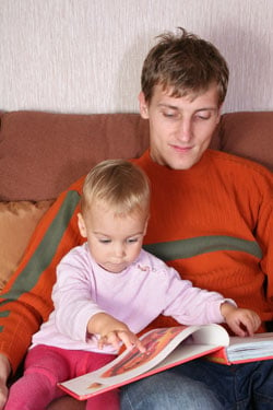 father reading a book with young daughter
