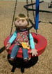 Sally the puppet, holding a ball on a playground.