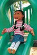 Carmen the puppet, sliding down a playgound slide.