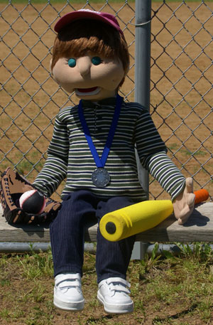 Corey the puppet, sitting on the side of a playground merry go round.