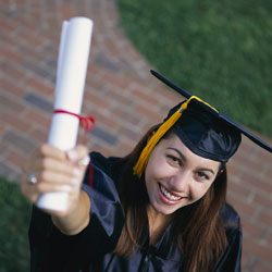 Young woman in graduation cap and gown, holding up her college degree