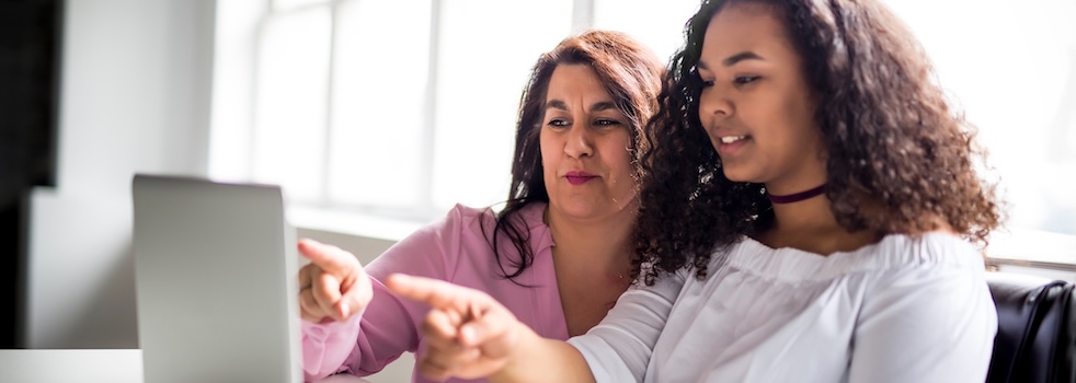 Two women, one older and one younger, looking at something together with focused expressions.