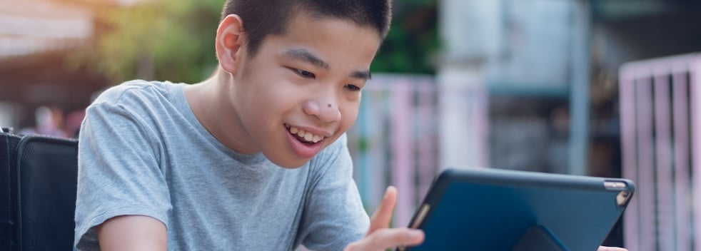 Child smiling and reading on a tablet