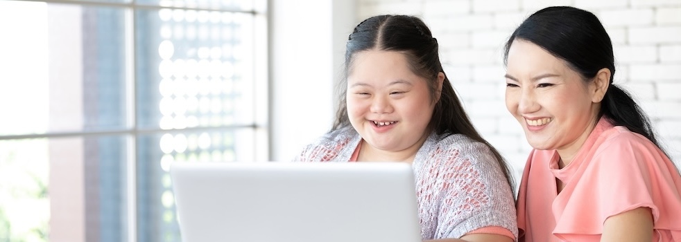 down syndrome teenage girl and her teacher using laptop computer together on a table