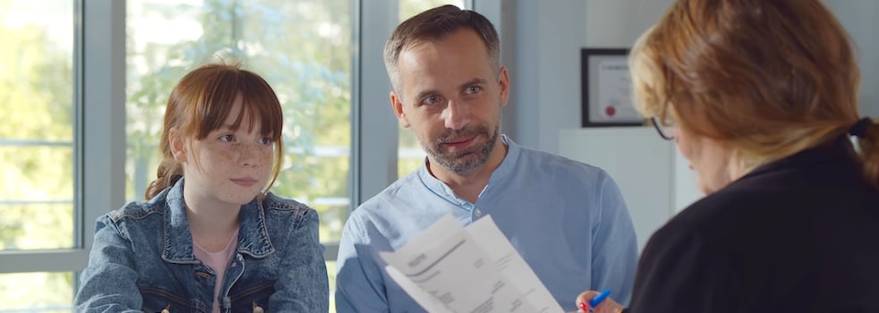 Back view of female headmaster interview father and preteen girl in school office. Smiling mature man with teenage daughter meeting woman principal
