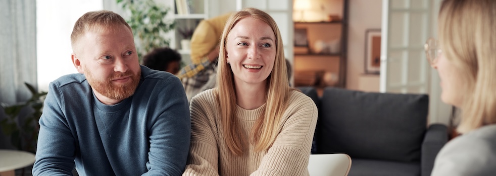 Happy foster couple answering questions from social worker at table during their meeting at home