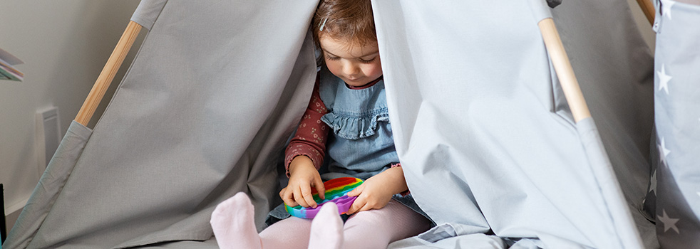 Young child sitting in a sensory tent with a pop fidget in their lap